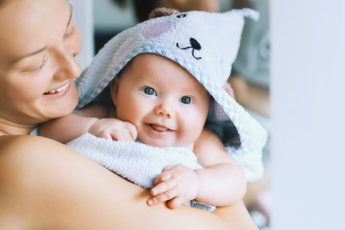 Süßes Baby bei der Mama auf dem Arm mit Handtuch