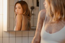 Frau vor Spiegel im Badezimmer