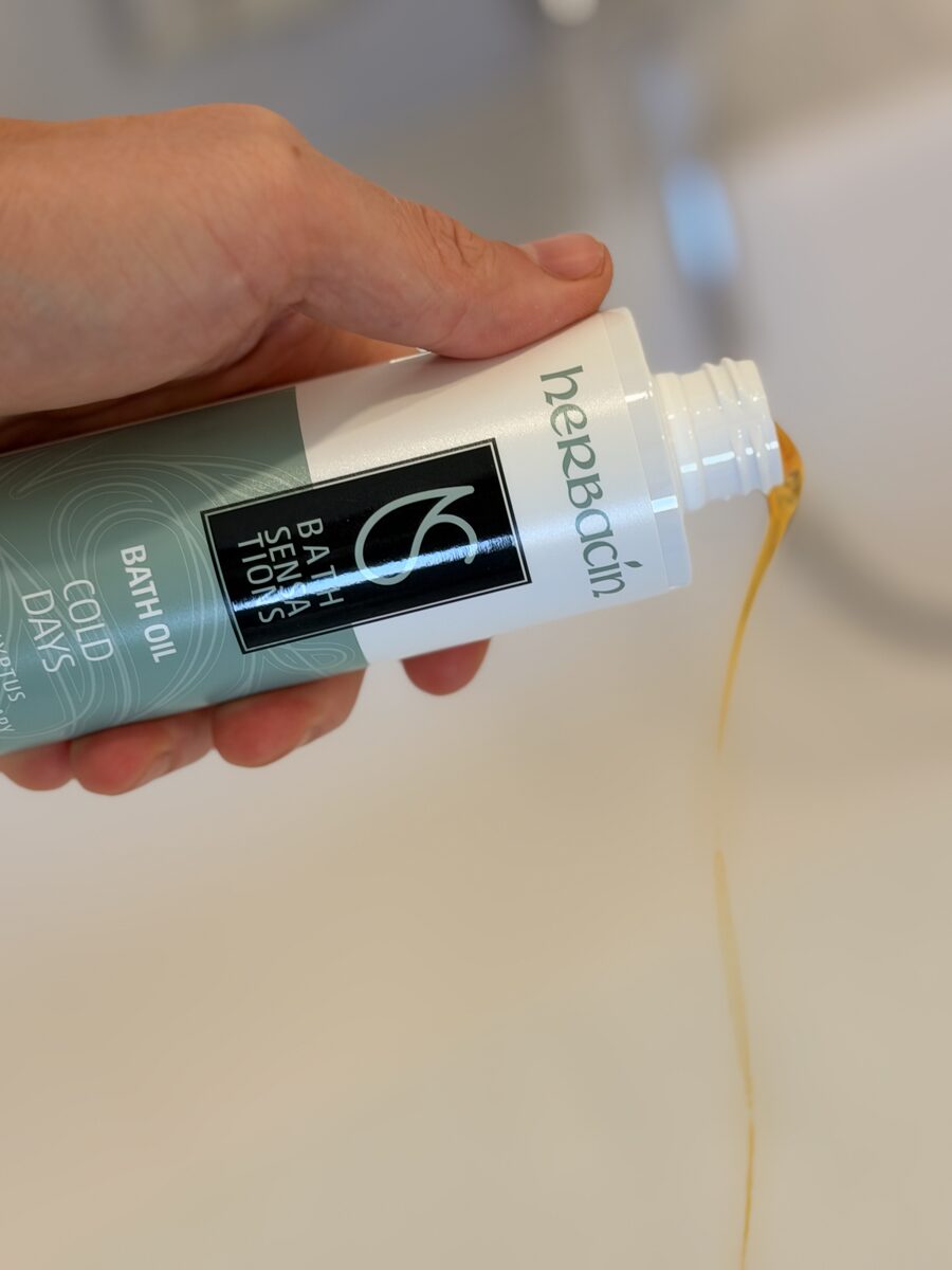 Dünnflüssiges Herbacin Badeöl wird aus der Flasche in die Badewanne gegossen